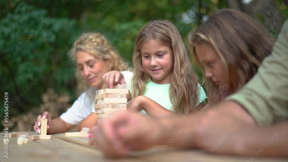 Family playing jenga outdoors, concentration and fun