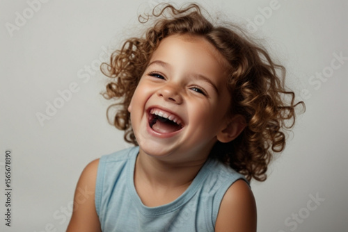 A young child with curly hair laughs heartily showing teeth in a joyful expression of happiness and glee created with generated ai