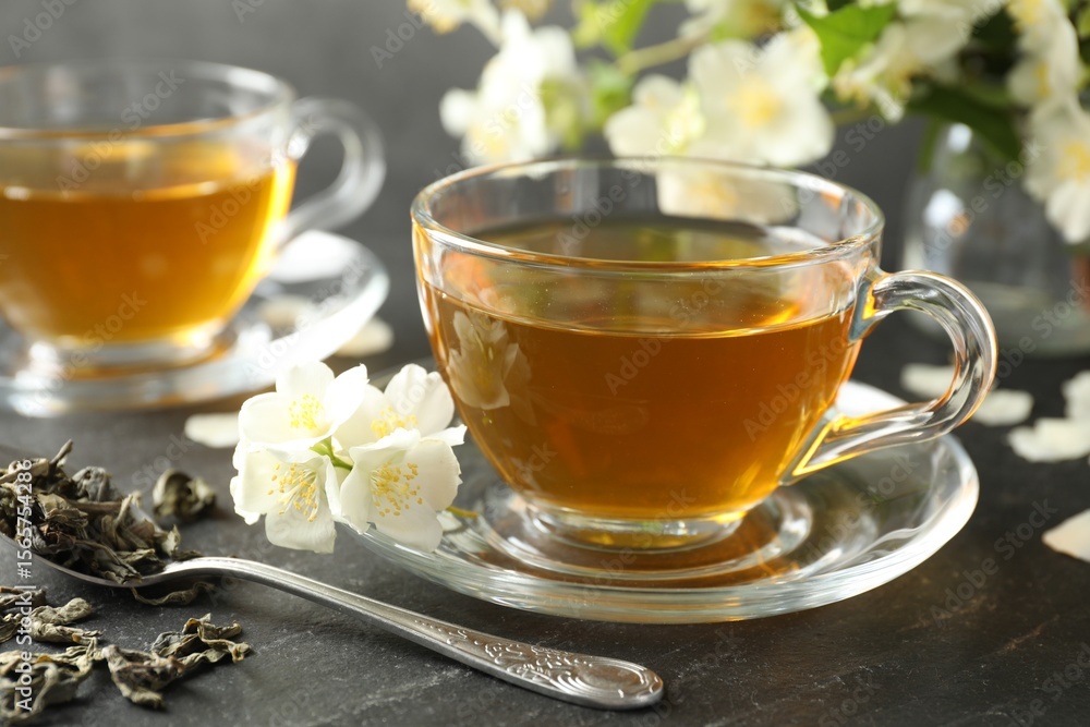 Aromatic jasmine tea, brew and flowers on grey table, closeup Aromatic jasmine tea, brew and flowers on grey table, closeup