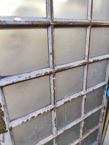 Rusty Vintage Industrial Window with Frosted Glass Panels and Weathered Metal Grid Frame Close-Up