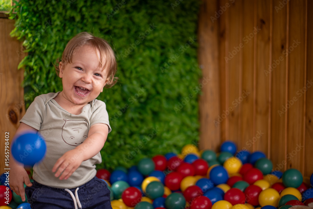Fototapeta premium Baby having fun in the ball pit throwing a ball