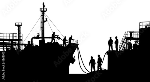 Silhouetted tanker ship undergoing transfer operations, workers connecting hoses, busy port activity.