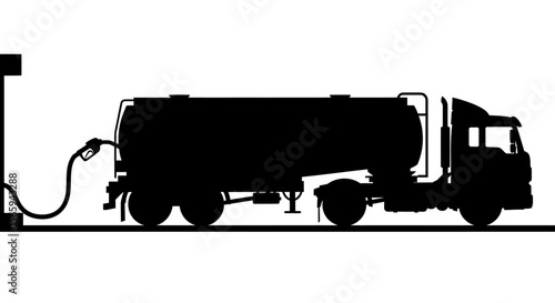 Silhouette of a fuel tanker truck being filled at a gas station.