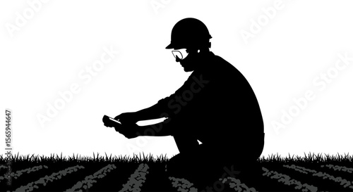 A silhouetted agricultural engineer examines soil sample in a field.