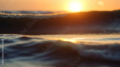 Close up of ocean waves during golden hour, the sun on the horizon casts a warm glow on the water. The gentle movement of the waves creates a peaceful and serene atmosphere with water ripples