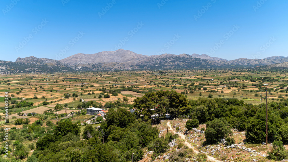 Obraz premium Stunning view of Lasithi Plateau in Crete, Greece showcasing agricultural land and mountains