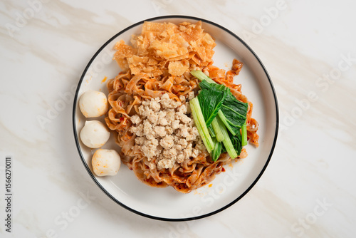 Spicy Asian Chili Oil noodles with minced chicken, fish balls, and vegetables served on plate. Perfect for recipes, articles or any cooking content.