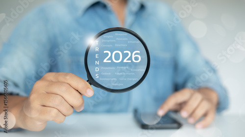 Foto Hand holding magnifying glass focusing on 2026 trends keywords, representing business innovation, market forecast, and future strategy analysis