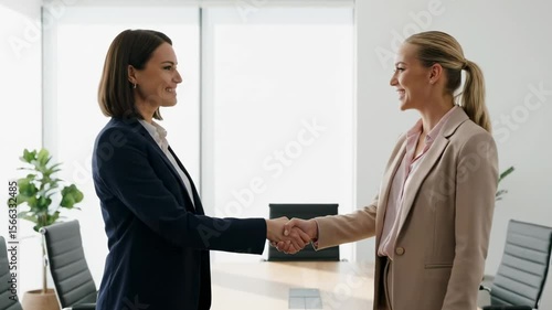 Wallpaper Mural Two businesswomen in suits shake hands in an office setting Torontodigital.ca