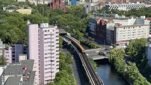 Aerial view of a yellow u-bahn train on an  elevated train track running through a Berlin Kreuzberg cityscape