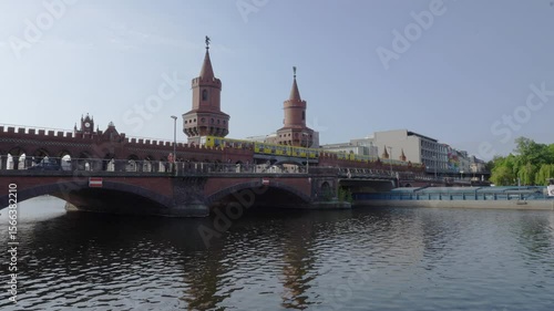 cityscape of Berlin showing spree river, and an U-Bahn train and a ship crossing Oberbaum bridge connecting the districts of Kreuzberg and Friedrichshain