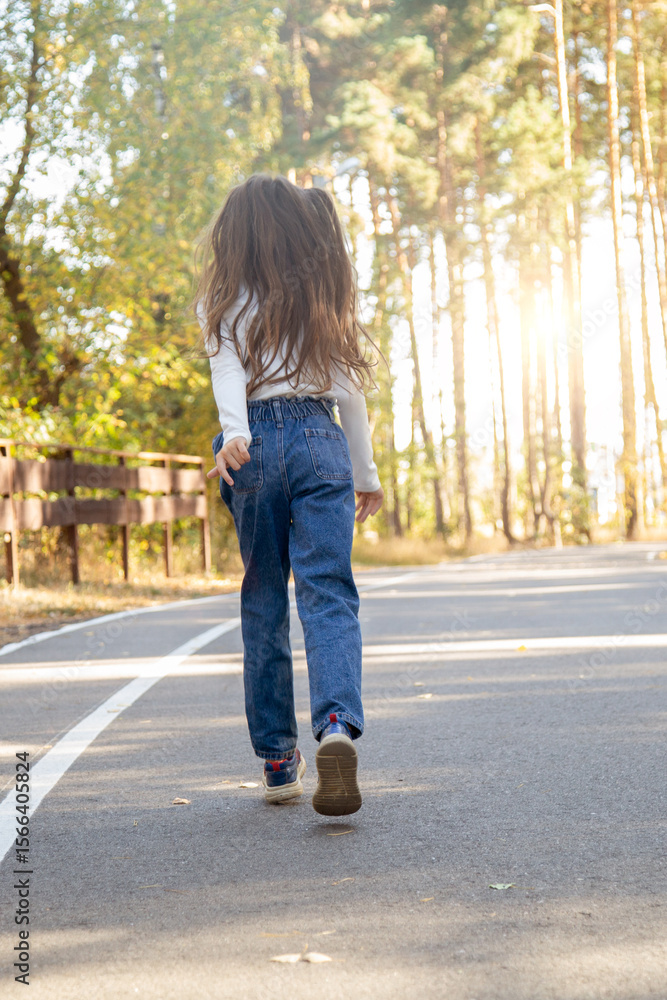 Rear view of a little child girl walking alone in green park. Rear view of a little child girl walking alone in green park.