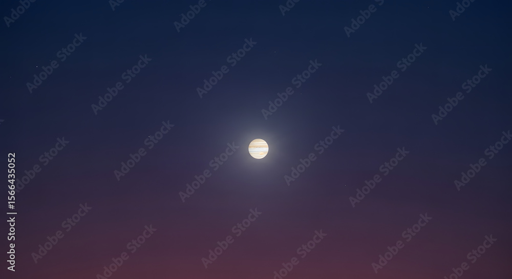 The planet Jupiter shines brightly in the dark, starry night sky with a gradient of blue to red color. The planet Jupiter shines brightly in the dark, starry night sky with a gradient of blue to red color.