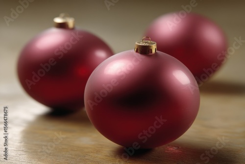 Three red christmas ornaments sitting on top of a wooden table