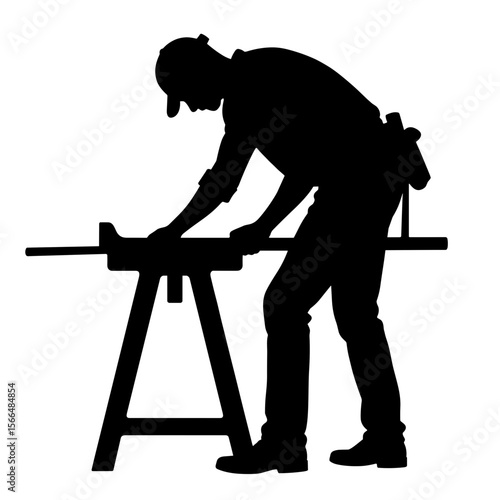 Worker shaping wood while standing at workbench in silhouette  