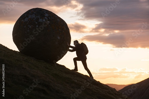 Man pushing giant boulder uphill at sunset, symbol of struggle perseverance determination and strength.
