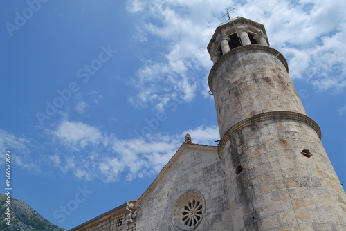 Close-up of Historic Stone Bell Tower and Church Facade in Perast, Montenegro, under Blue Sky