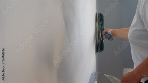 Protective Gloves On Her Hands, This Skilled Female Construction Worker Works Carefully With A Putty Knife To Repair And Even Out A Wall Surface.