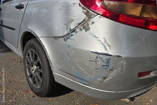 Rear-end collision damage on silver car with visible scrapes and paint transfer