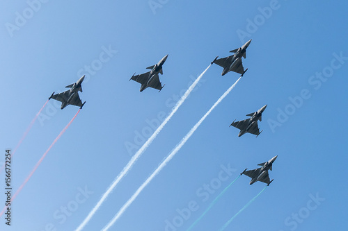 Five gray fighter jets with red white green colors in the blue sky