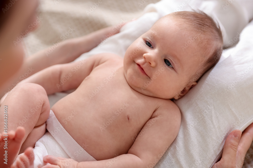 Mother putting her cute newborn baby to sleep on bed at home, above view Mother putting her cute newborn baby to sleep on bed at home, above view