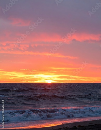 Ocean sunset with fiery sky reflecting on the water, waves