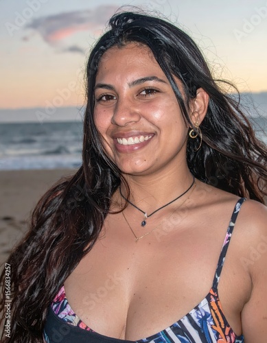Smiling young woman with long dark hair on a beach at sunset