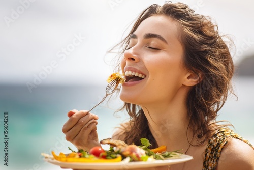 Beautiful young woman delightedly enjoying a vibrant, healthy meal outdoors, eyes closed in pure bliss, celebrating wellness and mindful eating in a scenic natural setting.