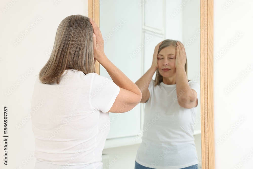 Fototapeta premium Beautiful senior woman near mirror indoors, selective focus