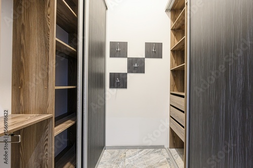 well-organized walk-in closet with wooden shelves, drawers, sliding doors, and wall-mounted hooks in a modern design