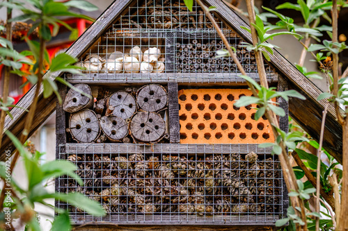 Insect hotel showcasing diverse materials for shelter in a lush garden setting during daylight hours