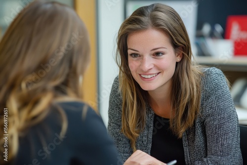 Wallpaper Mural Smiling woman engages in conversation with her colleague during a professional meeting at the office, Smiling pretty woman talking with her colleague while sitting by the table at office Torontodigital.ca