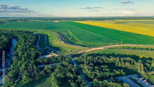 Aerial photo of a rural park and river next to contrasting green and yellow farm fields. Summer landscape.