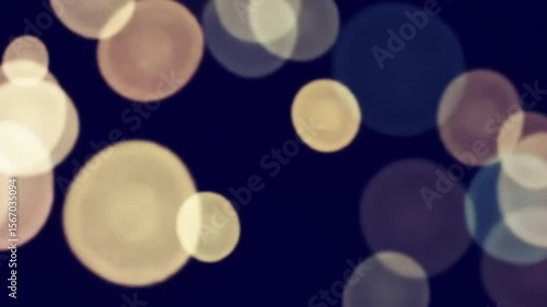 Abstract bokeh lights float gently on a dark background creating a soft effect