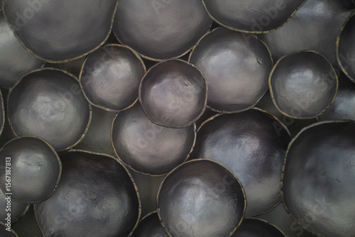 Abstract close-up of clustered metallic black ceramic bowls with subtle sheen and organic contours. The image features a soft play of light and texture, creating a sculptural, artistic composition per