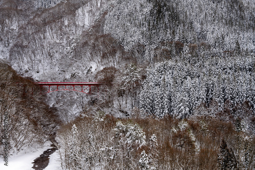 雪景色に映える赤い高井橋と山田温泉付近の冬の渓谷（長野県）/ Red Takai Bridge and Winter Gorge near Yamada Onsen in Snowy Nagano, Japan