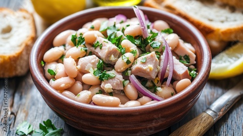 A bowl of tuna and white bean salad with red onion and parsley is served