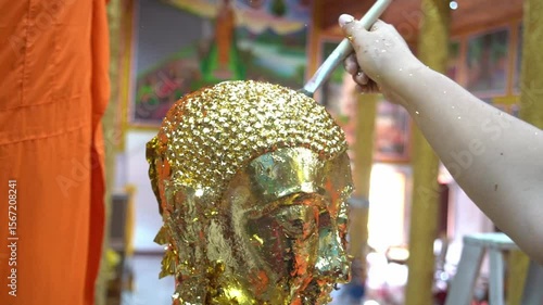 Goldsmith applies Thai gold patterns to Buddha statues using gold sheets.