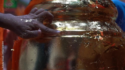 Goldsmith applies Thai gold patterns to Buddha statues using gold sheets.