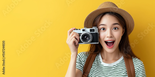 Enthusiastic Young Woman Holding Vintage Camera Against Bright Yellow Background, Ready to Capture Exciting Moments on Adventure, Travel, and Fun Experiences