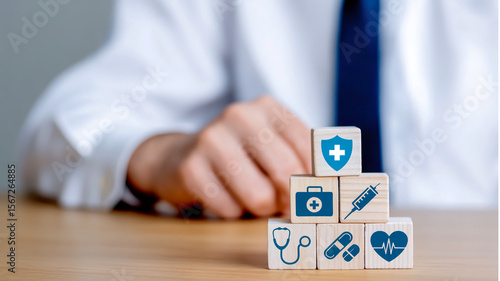A professional healthcare-themed composition featuring a hand placing a white wooden cube with a blue medical shield icon on top of a stack of similar cubes.