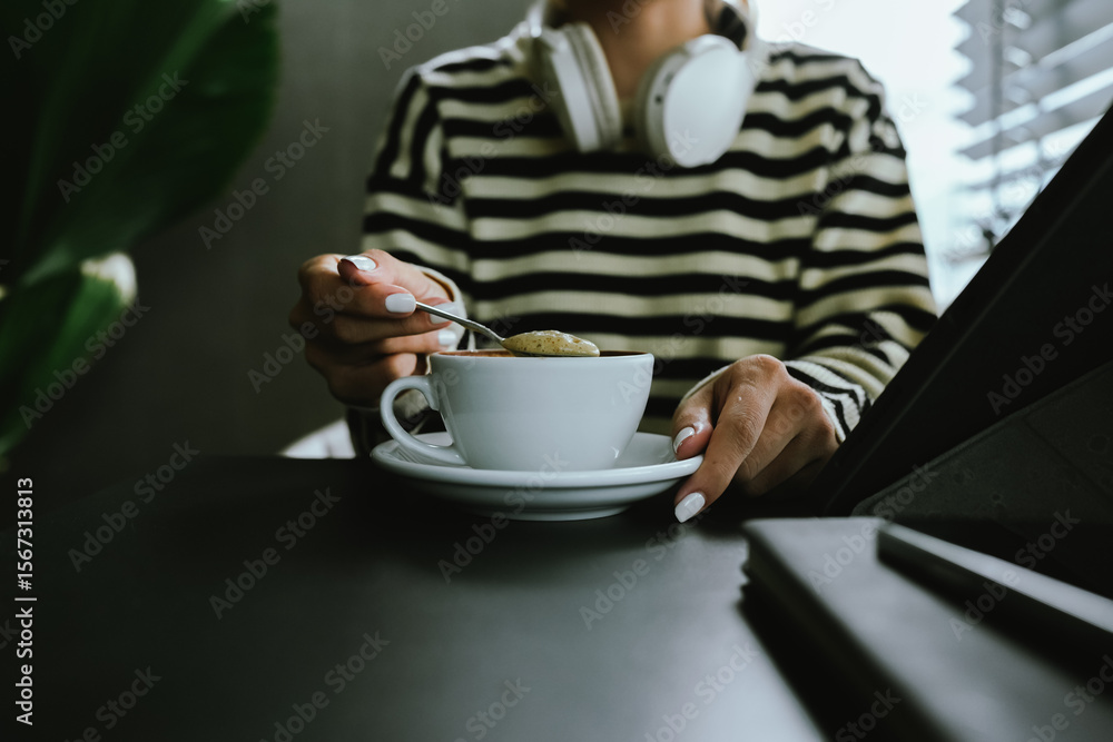 Close-up of a woman holding a glass of latte to create warmth, comfort and calmness during a quiet morning coffee break at home or at work. Close-up of a woman holding a glass of latte to create warmth, comfort and calmness during a quiet morning coffee break at home or at work.