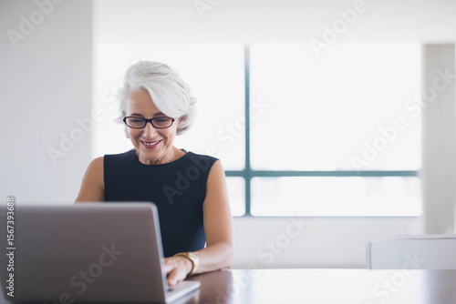 Confident Mature Woman Using Laptop by Window - Age Diversity in Workplace