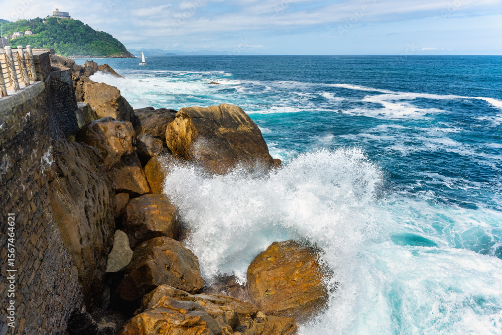 Fototapeta premium Big wave breaking on the rocks on the promenade of the tourist city of San Sebastian, Donostia.