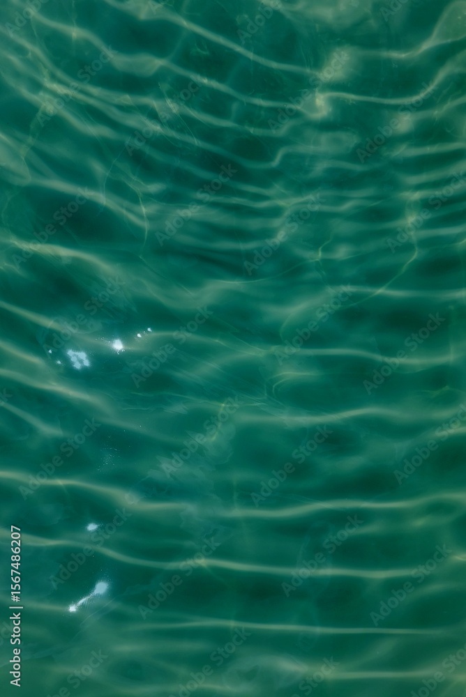 Obraz premium Blue water with ripples on the surface. Defocus blurred transparent blue colored clear calm water surface texture with splashes and bubbles. Water waves with shining pattern texture background.