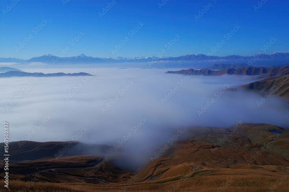 Aerial view of mountains covered in fog under a clear blue sky on a sunny day landscape scene Aerial view of mountains covered in fog under a clear blue sky on a sunny day landscape scene