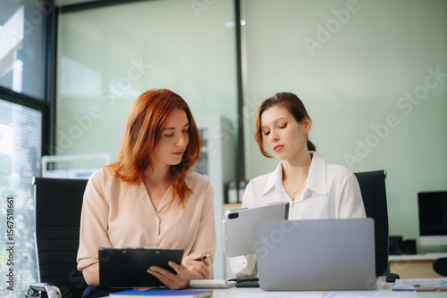 Two business workers talking on the smartphone and using laptop at the office.