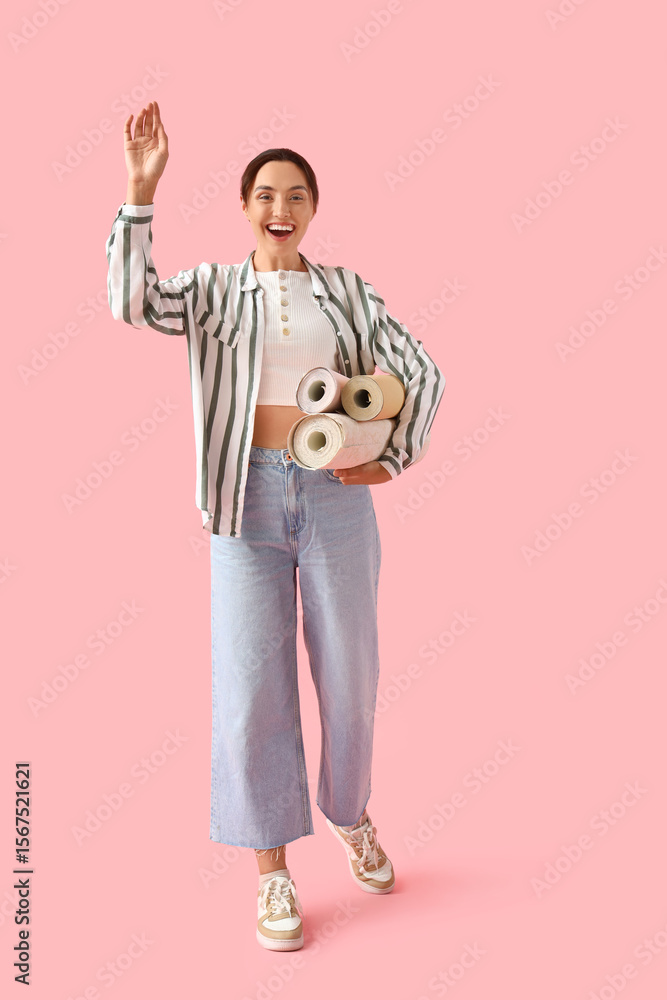 Young woman with wallpaper rolls on pink background Young woman with wallpaper rolls on pink background