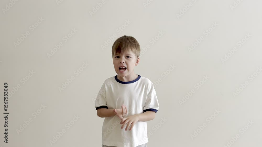 Young Caucasian boy in a light t-shirt shaking his head in disapproval. He expresses refusal, disagreement, or dissatisfaction with facial expression and body language. Concept of childhood emotions. Young Caucasian boy in a light t-shirt shaking his head in disapproval. He expresses refusal, disagreement, or dissatisfaction with facial expression and body language. Concept of childhood emotions.