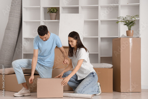 Young couple taping box in ...